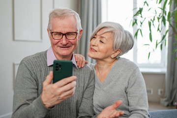 Video call. Happy senior couple woman man with smartphone having video call. Mature old grandmother grandfather talking speaking online. Older generation modern tech usage. Virtual meeting online chat