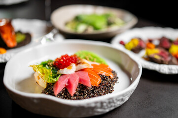 A beautifully plated poke bowl featuring fresh salmon, tuna, quinoa, and fish roe on a dark background