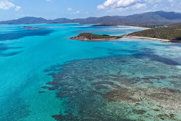 Fototapeta premium A breathtaking aerial view of Hydeaway Bay on Queensland’s Whitsunday Coast. The turquoise waters, white sandy beaches, and lush tropical landscape create a serene coastal paradise.