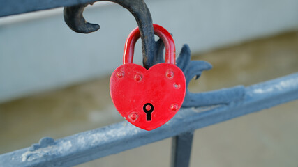 Red heart-shaped love lock on metal railing symbolizing affection and romance