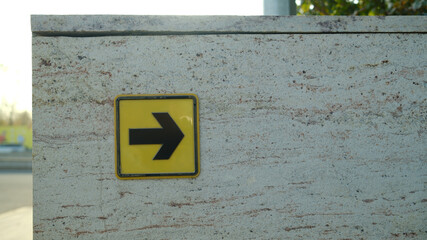 Yellow navigation arrow sign on textured stone wall