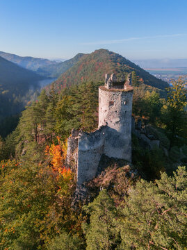 Aerial view of the ancient Blatnica castle ruins standing proudly on the hill amidst the colorful autumn trees, Blatnica, Zilinsky kraj, Slovakia.