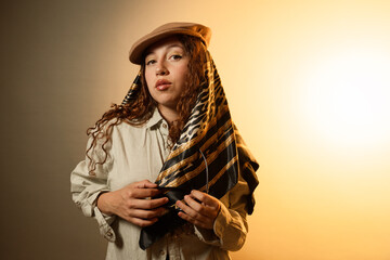 Woman holding patterned silk scarf wearing newsboy hat