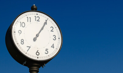 Vintage outdoor clock against clear blue sky with copy space