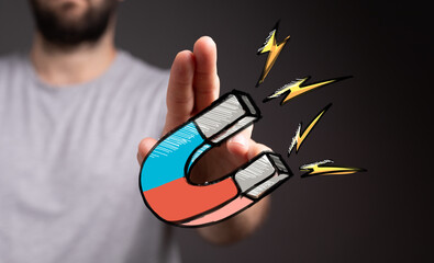 Stock photo of a hand holding a powerful magnet, symbolizing attraction and influence. Ideal for...