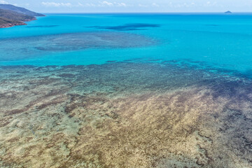 A breathtaking aerial view of Hydeaway Bay on Queensland’s Whitsunday Coast. The turquoise waters, white sandy beaches, and lush tropical landscape create a serene coastal paradise.
