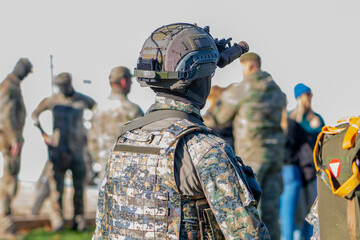A soldier wearing a helmet is watching people with a scope.