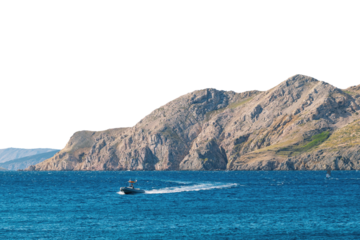 Small boat navigating blue waters near rocky island coastline. Isolated object