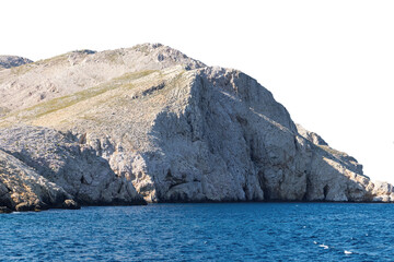 Rocky coastal cliff overlooking blue ocean water. Isolated object