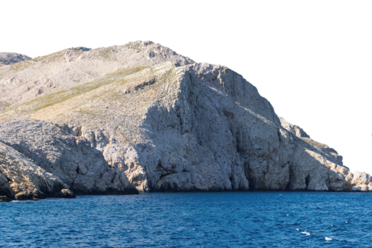 Rocky coastal cliff overlooking blue ocean water. Isolated object
