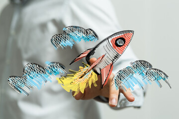 Hand holding a drawn rocket, representing concepts of launch, growth, and startup success. Idea of...