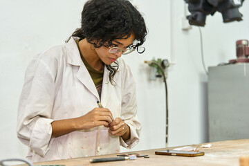 Woman artist focusing on craft details in workshop