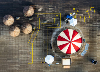 Aerial view of a dynamic scene with a red and white striped tent, surrounded by geometric yellow lines, leading to smaller tents and a lone vehicle, Tel Aviv-Yafo, Tel Aviv District, Israel.