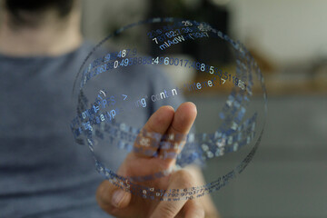 A person's finger touching a digital sphere with data and code floating, representing modern technology, information and innovation.