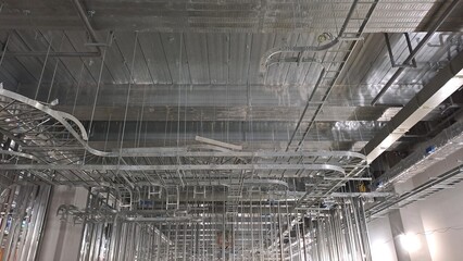 dense network of overhead metallic cable trays and infrastructure in commercial building ceiling construction