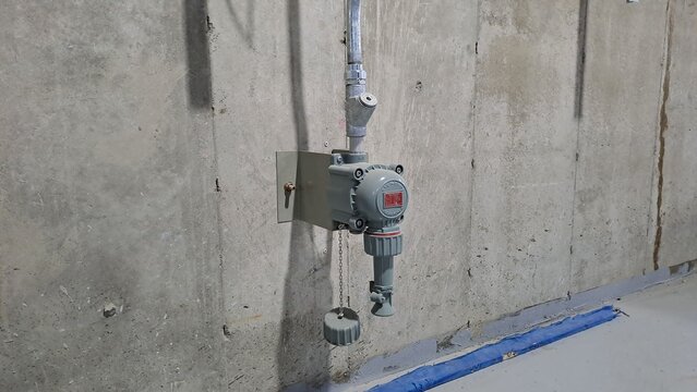 industrial explosion-proof junction box or sensing device mounted on a concrete basement wall