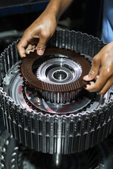 A technician's oily hands assembling a clutch friction plate onto the metallic hub of an automatic...