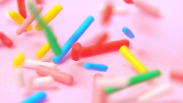 rainbow hued sprinkles descending softly against tranquil pink background, embodying spirit of joy and celebration, macro