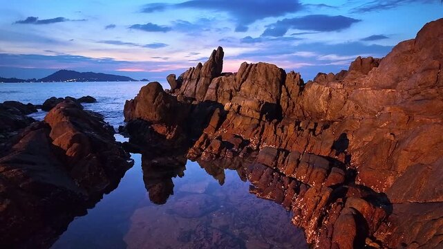 Majestic mountains rise under sky at night, reflecting in tranquil ocean waters, creating serene and captivating landscape of nature beauty