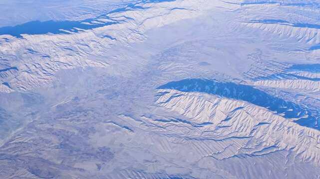 arial view from plane on mountain ridge, showcasing natural elegance of winter landscapes and enveloping viewers in calming wilderness, motion