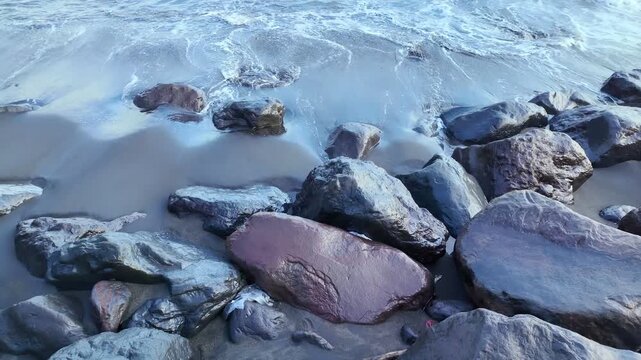 waves crash against rugged black volcanic rocks in Bali, Indonesia, creating an awe inspiring scene of nature raw energy and timeless landscapes of Ubud