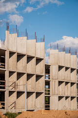 A construction site showcases a unique concrete building with exposed beams under a blue sky