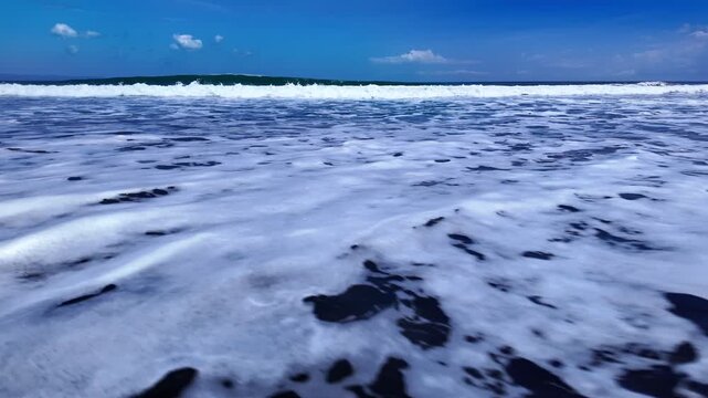 beauty of Bali shores highlighted by black volcanic rocks and surging waves, creating dramatic yet calming atmospheric landscape of Ubud