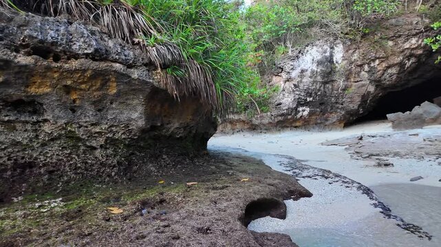 Panorama of picturesque bay features tidal movements within rugged cave, reflecting Indonesia geology and captivating ocean interactions with tranquil ambiance, slow motion