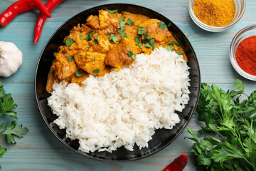 Chicken tikka masala with rice and spices on light blue wooden table, flat lay