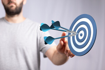 Close up of a man's hand holding a dart towards a target. Conceptual shot of business goals,...