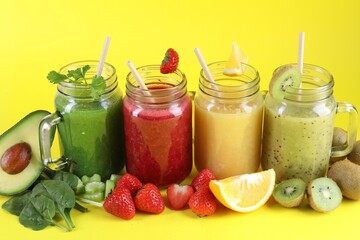 Different tasty smoothies in mason jars and ingredients on yellow background, closeup