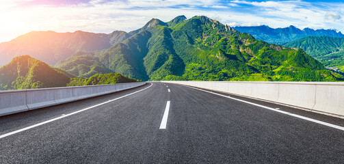 Empty asphalt highway road and majestic mountain natural landscape under a beautiful blue sky with clouds