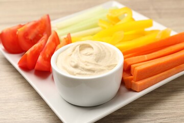Different fresh vegetables and sauce on wooden table, closeup