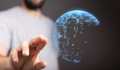 A person's hand touching a glowing digital globe, representing technology, connection, and the...