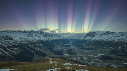 Breathtaking view of the aurora borealis illuminating the winter sky over a vast mountainous landscape with snow covered peaks and a valley below at nighttime.