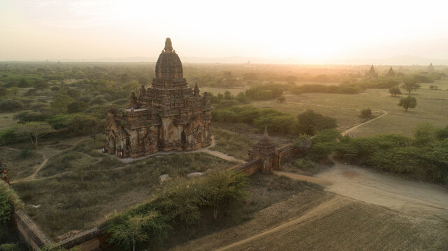 Aerial view of the ancient temple basking in the soft, golden light of dawn, its weathered stone contrasting with the surrounding flat landscape, Old Bagan, Mandalay Region, Myanmar (Burma).