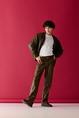 Handsome man showcases fashionable style against a vibrant red background in a modern setting