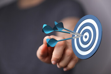 Hand pointing at target with darts, success, goals, aiming, accuracy, business strategy,...