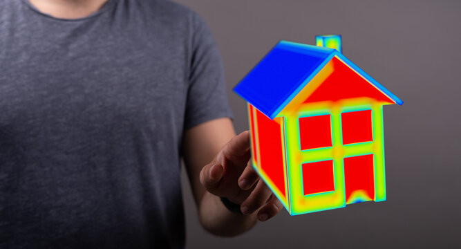 A person holds a colorful house, symbolizing ideas, concepts and the process of purchasing a home. Visual representation of house and home relat