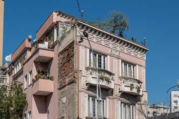 Verzierte Fassade eines rosa Altbaus mit Balkon im Sonnenlicht, Tirana, Albanien