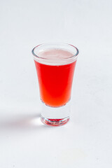 A vibrant red beverage fills a clear shot glass, inviting cheers and delight