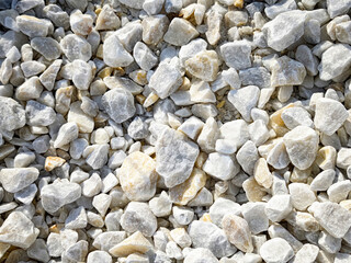 White gravel stones in a sunny outdoor environment with ample space for text and a natural texture background