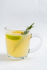 A clear mug holds a vibrant herbal drink with lemon and rosemary, perfect for relaxing