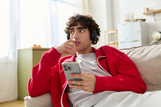 Stylish man enjoys music on his phone while relaxing in a cozy living room setting