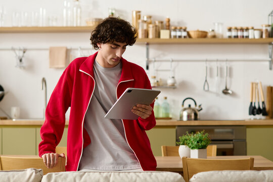 Stylish man engages with tablet in modern kitchen setting while showcasing fashion sense