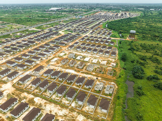Aerial view of rows of houses under construction, with their brown roofs contrasting the green surroundings, Abuja, Nigeria.