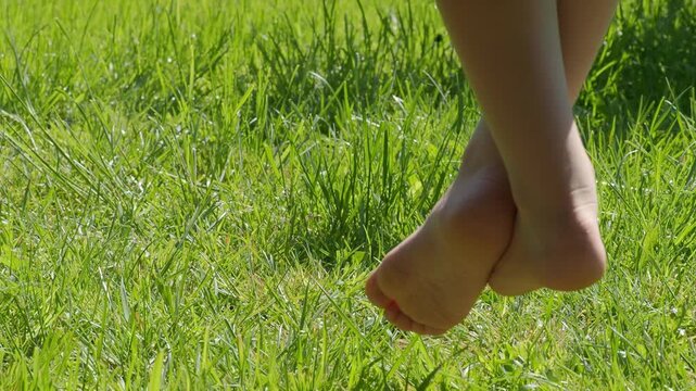 Close up Child dangles his legs while sitting on wooden park bench, against backdrop of cheerful green lawn. The vibe is one of spring youth, mood of adolescence, carefree bliss of childhood. 2026, 4K