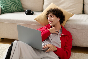 Stylish man relaxes on couch while working on laptop during afternoon