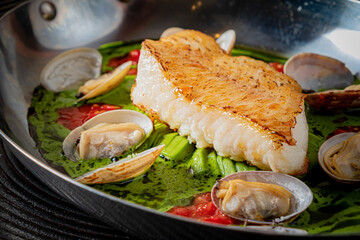 Seared fish fillet with clams and vibrant greens make a delightful dish