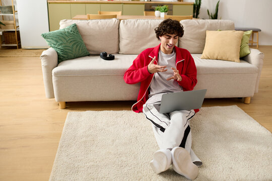 Handsome man enjoys casual video call while lounging in stylish attire at home